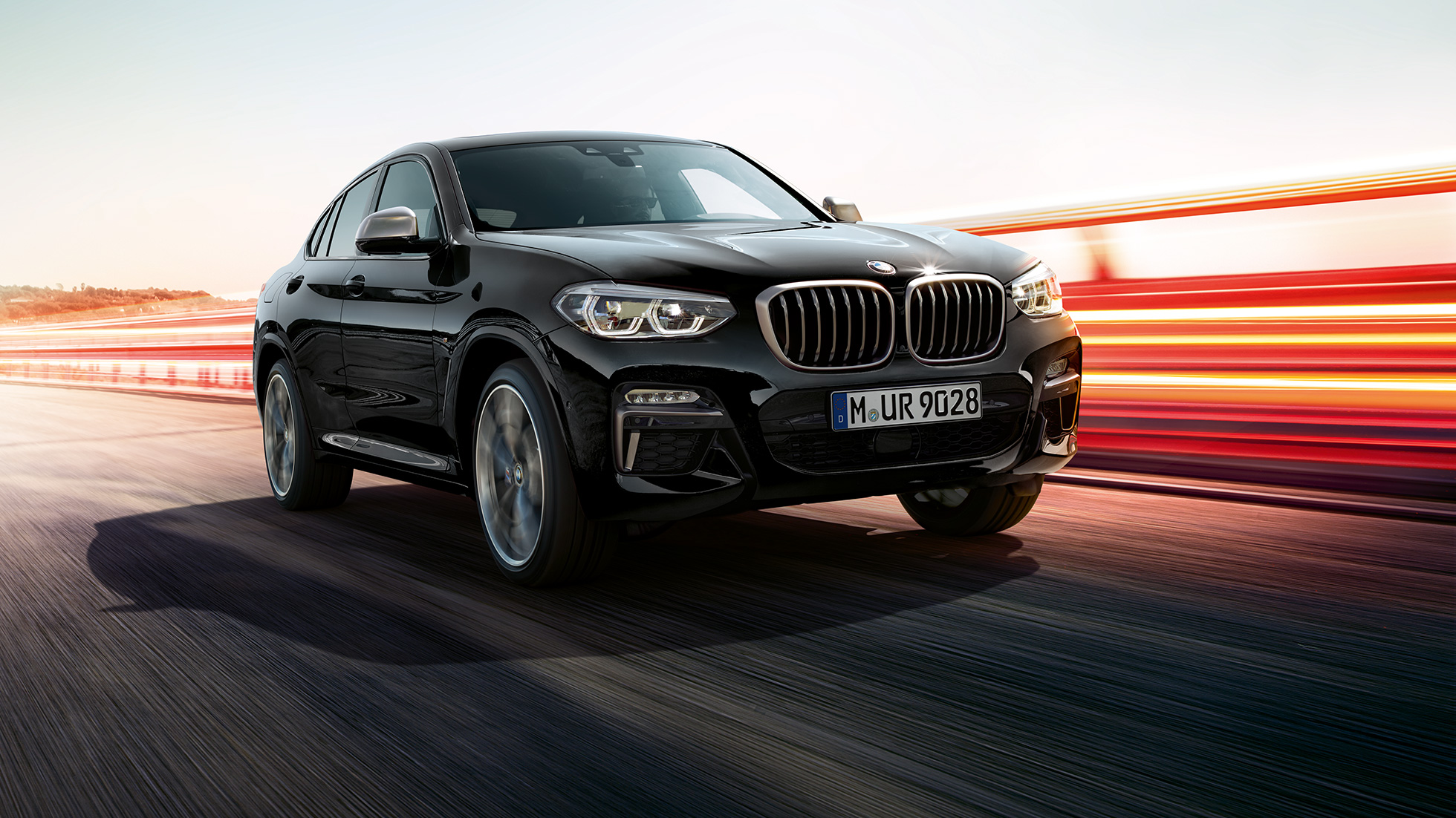 BMW X4 M40i и BMW X4 M40d, вид спереди с поворотом в три четверти. BMW X4 M40i и BMW X4 M40d в Black Sapphire металлик, экстерьер, вид спереди с поворотом в три четверти, левая сторона со световыми полосками.