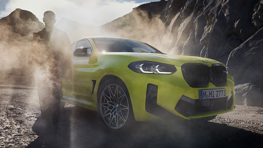 BMW X4 M Competition F98 LCI Facelift 2021 в кольорі Sao Paulo Yellow, вид спереду в три чверті з чоловіком в тумані