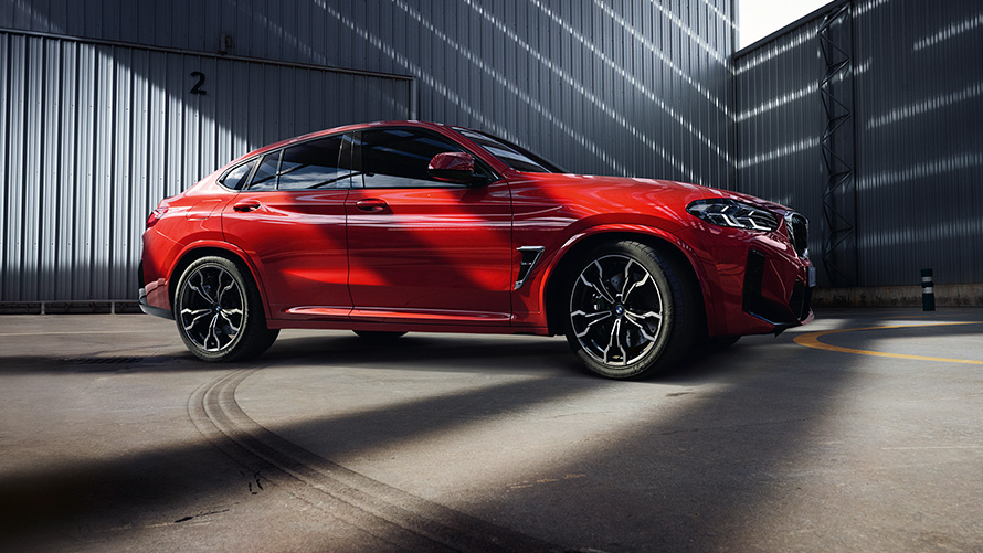 BMW X4 M F98 LCI Facelift 2021 в кольорі Toronto Red металік, вид збоку в три чверті перед фабрикою