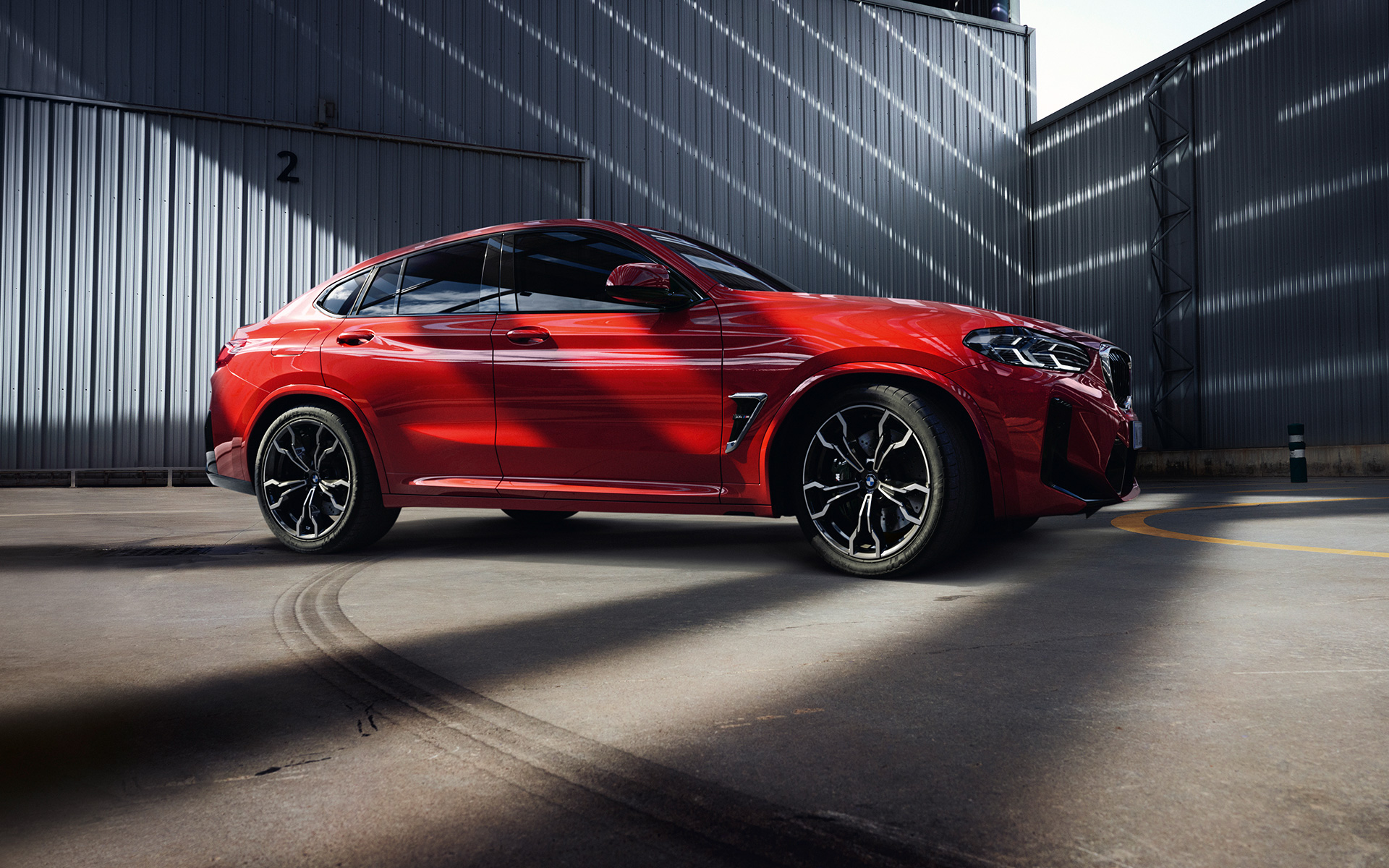 BMW X4 M F98 LCI Facelift 2021 в кольорі Toronto Red металік, вид збоку в три чверті перед фабрикою