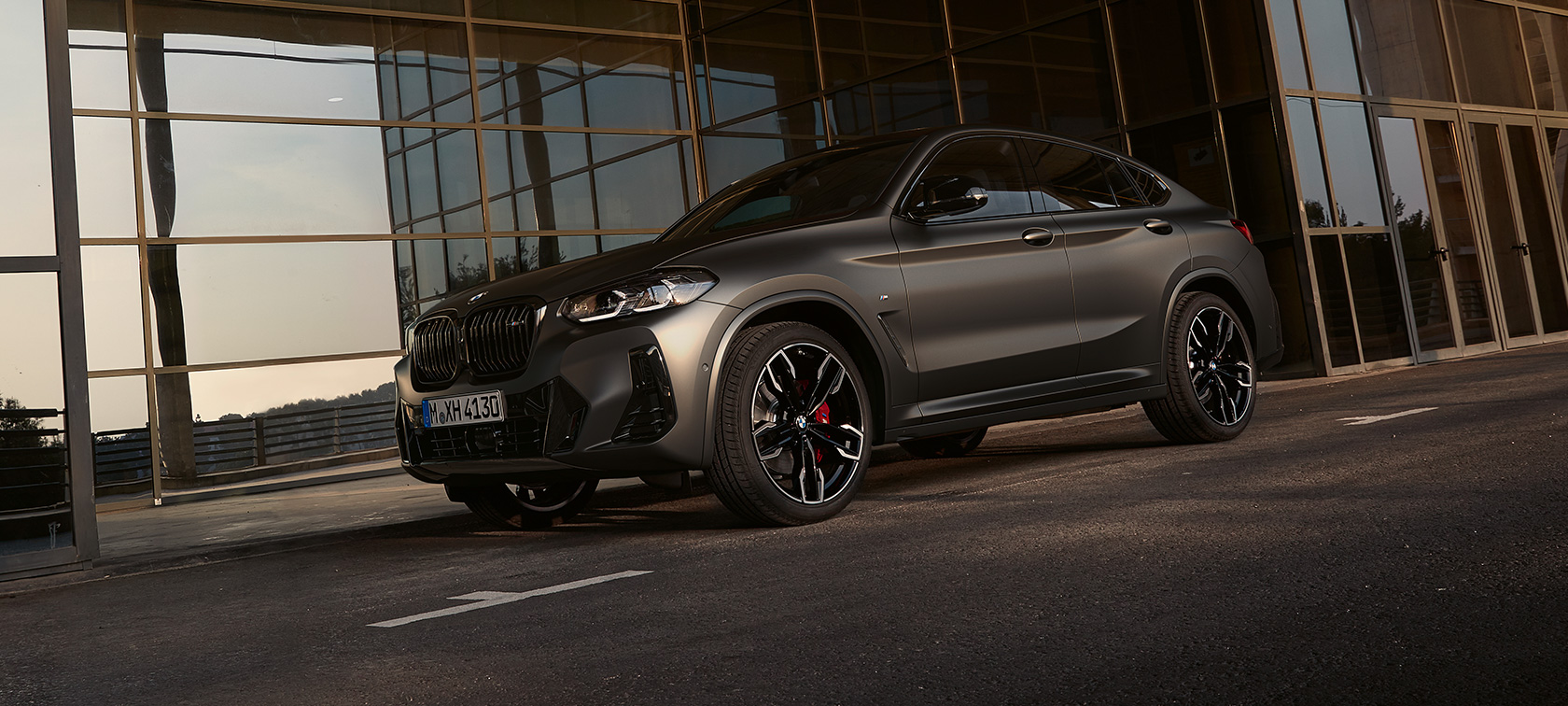 BMW X4 M40i G02 LCI 2021 Facelift, вид спереду в три чверті перед скляним фасадом