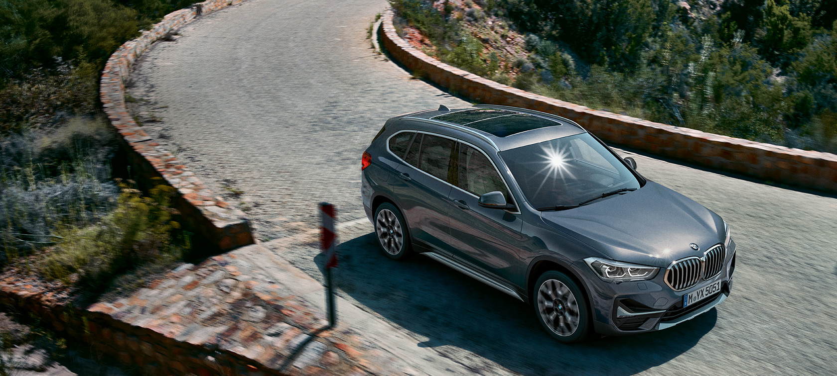 BMW X1, вид спереду з поворотом в три чверті. BMW X1, вид спереду з поворотом в три чверті на тлі гірського пейзажу.