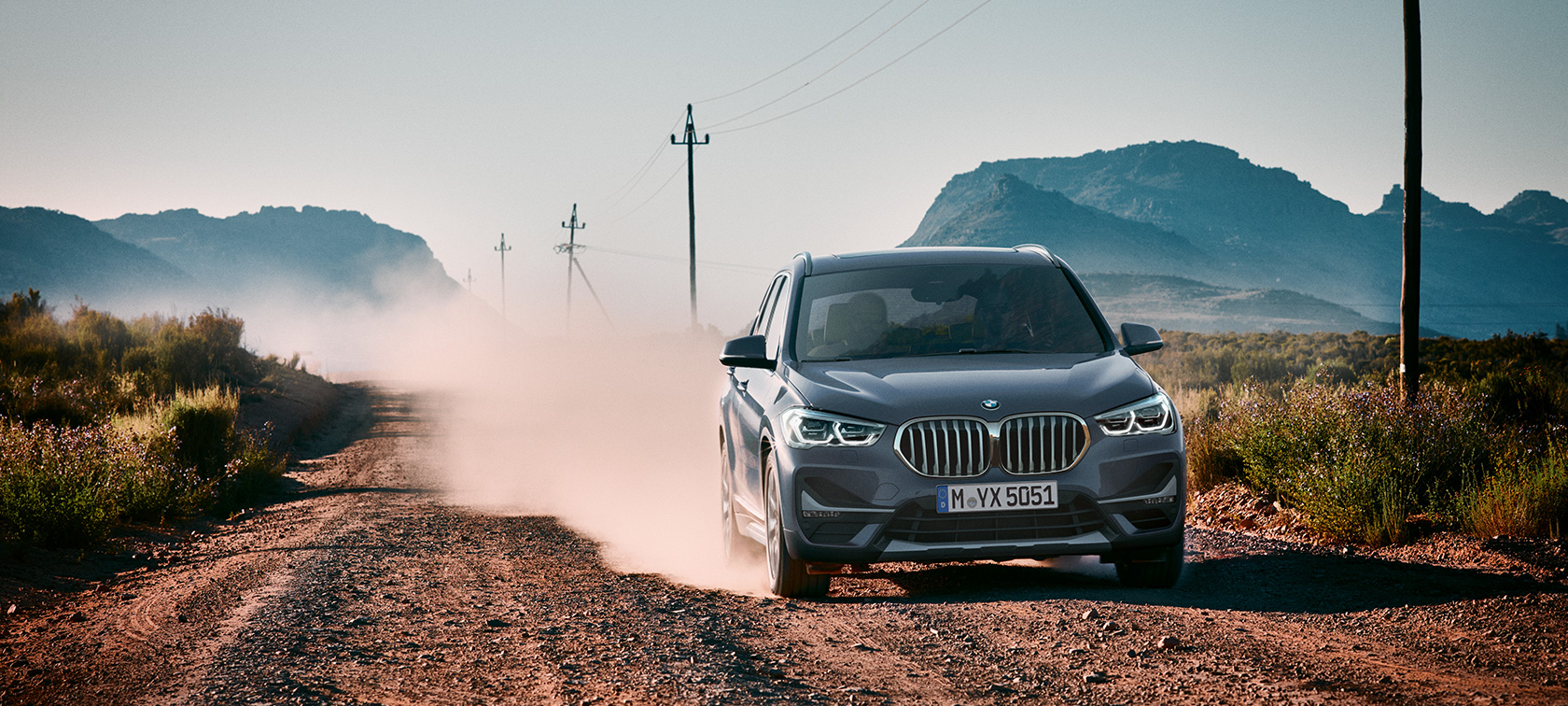 BMW X1, вид ззаду з поворотом в три чверті. BMW X1, вид ззаду з поворотом в три чверті на тлі гірського пейзажу.