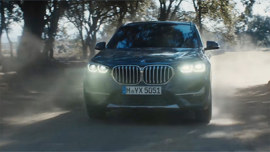 BMW X1 F48 LCI вид спереди в три четверти BMW X1 F48 LCI вид спереди в три четверти в движении, на фоне природного пейзажа