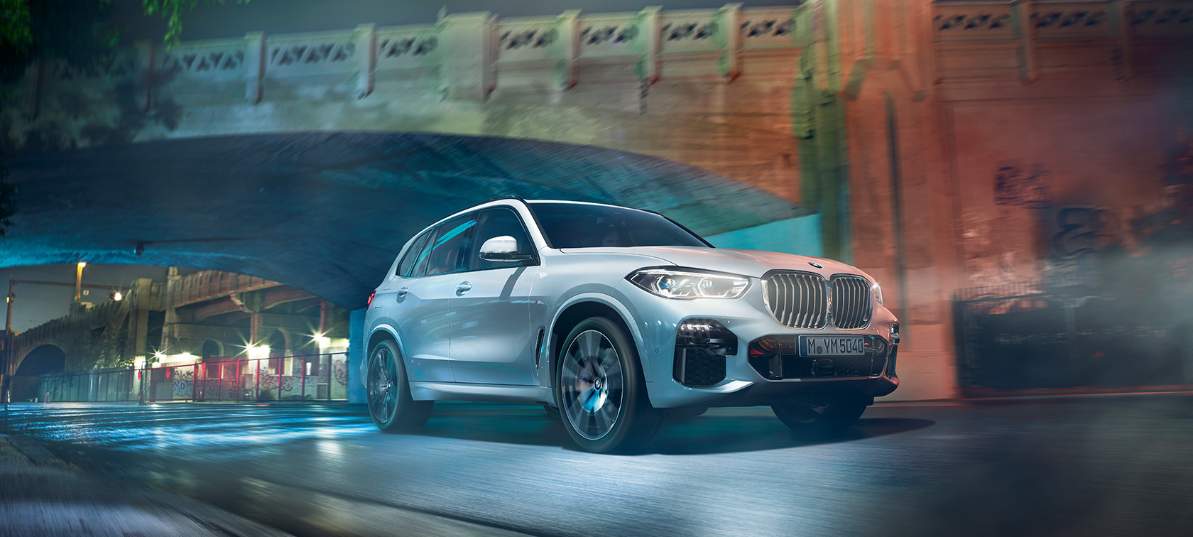 BMW Х5 G05 2018 у кольорі Mineral White metallic, вид на три чверті спереду під час руху в нічний час