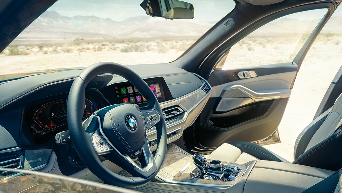 BMW X7 интерьер BMW X7 интерьер: вид снаружи на первый ряд сидений с видом на руль, приборную панель и кожаные сиденья