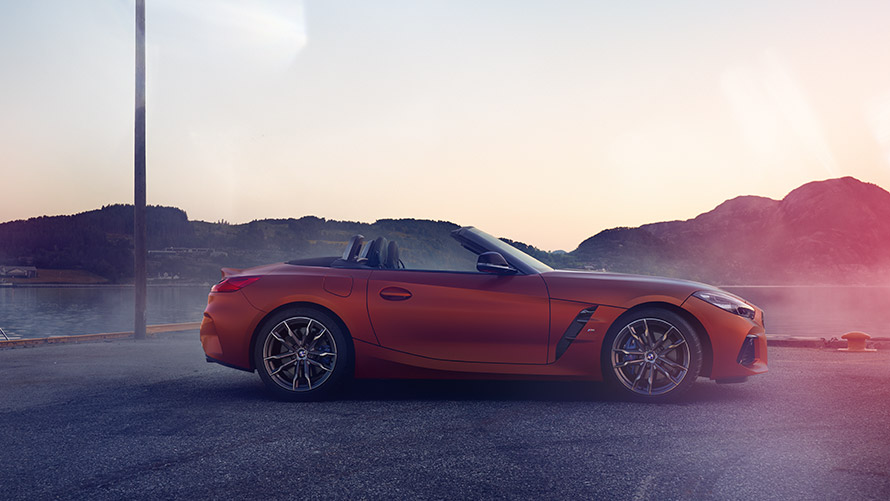 Оранжевый BMW Z4 First Edition на повороте Оранжевый BMW Z4 First Edition на повороте перед горным пейзажем