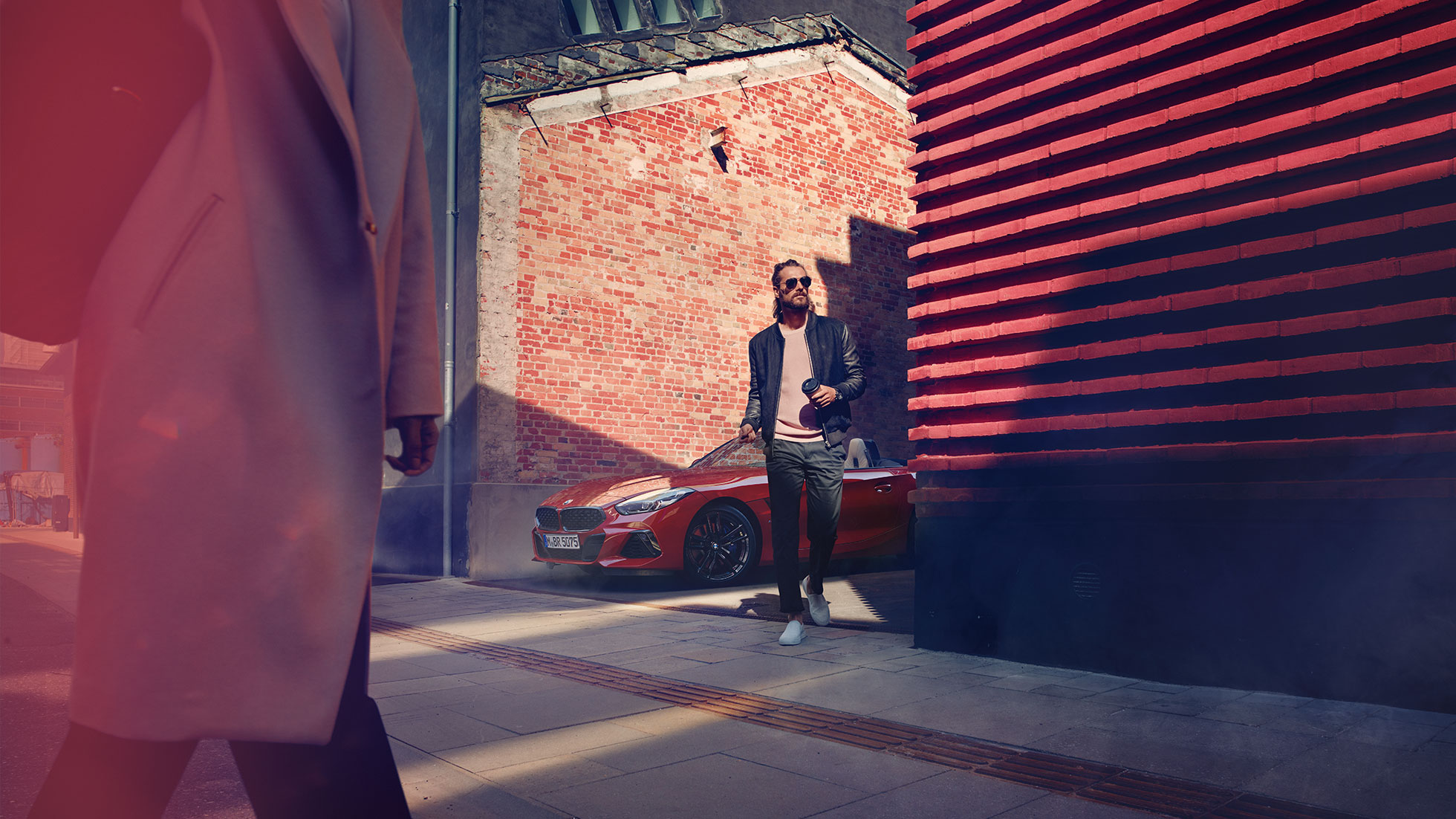 BMW Z4 Родстер в переулке Мужчина в переулке перед BMW Z4 Roadster