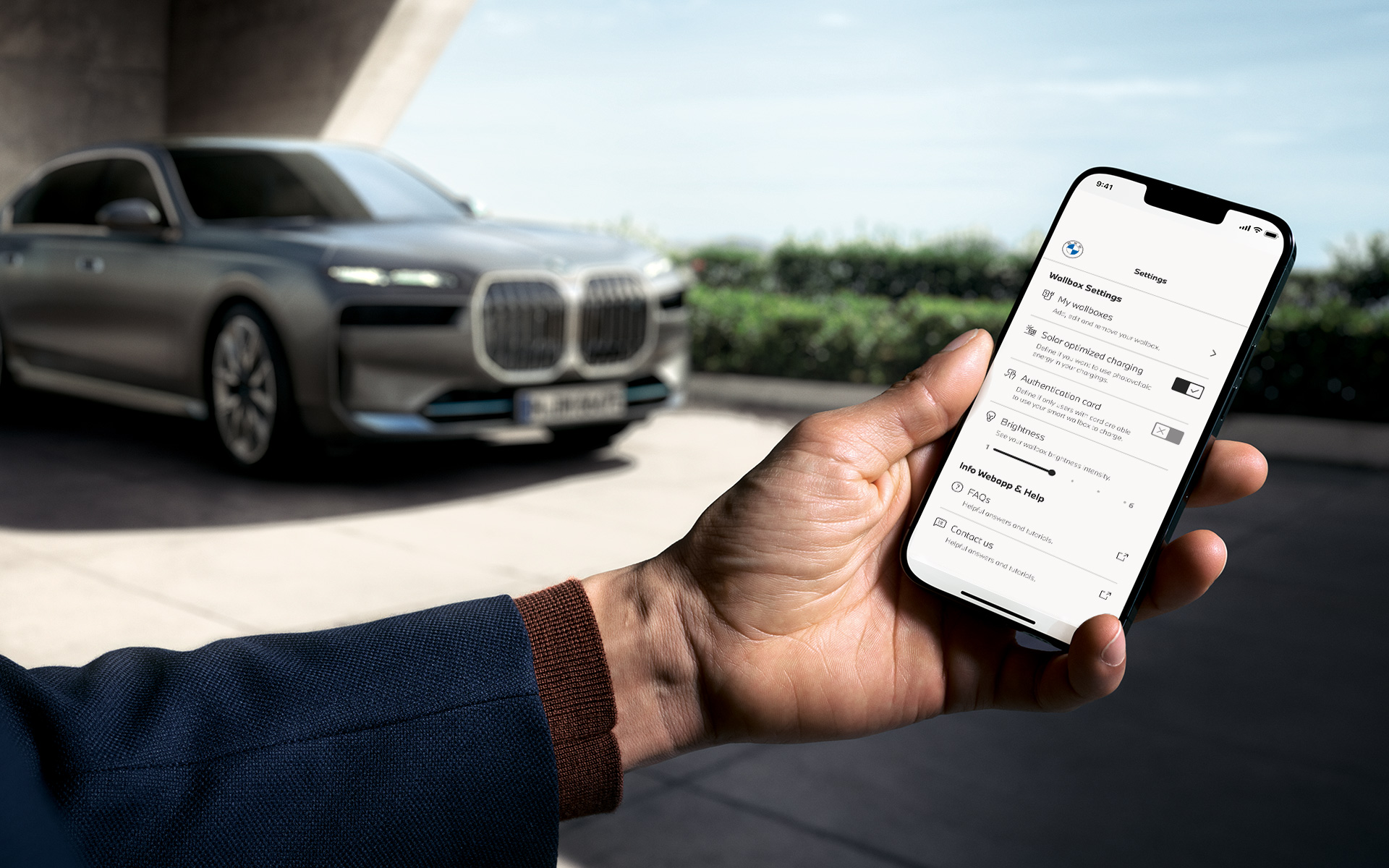 BMW i7 G70, смартфон на передньому плані показує застосунок My BMW 