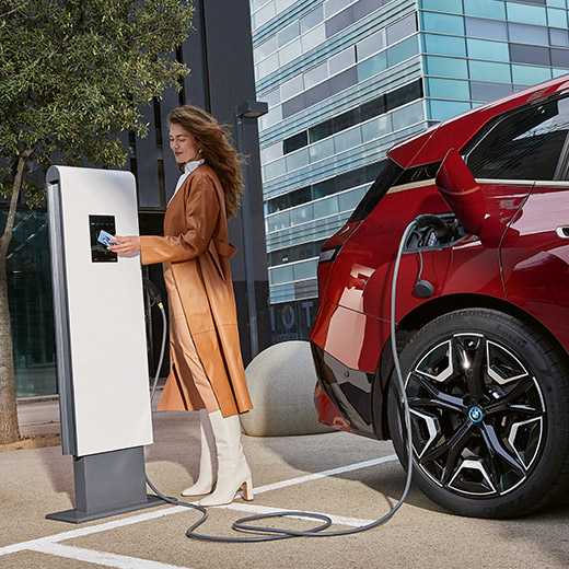 BMW iX i20 на зарядній станції, жінка з карткою BMW Charging 