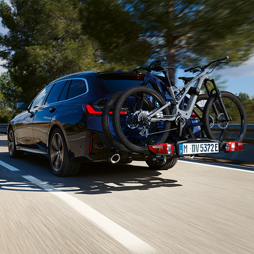 BMW 3er Touring G21 PHEV вид ззаду у три чверті з велосипедами в русі