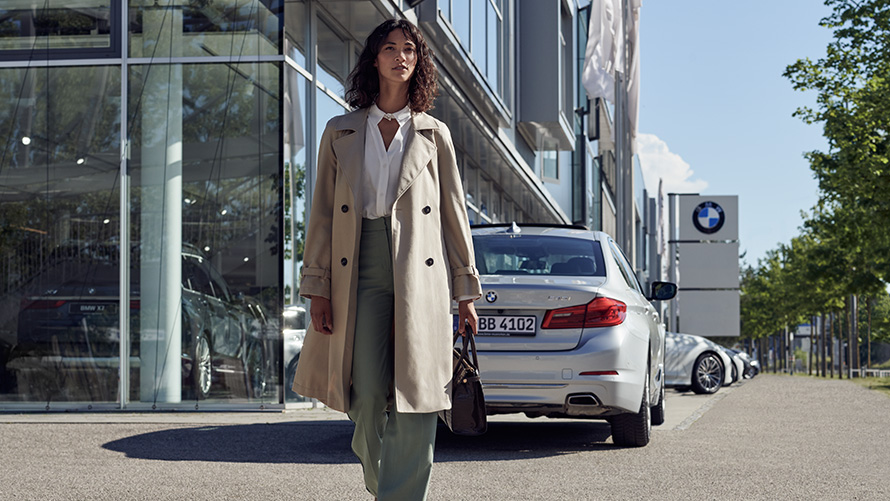BMW Service Inclusive Жінка перед дилерським центром BMW.