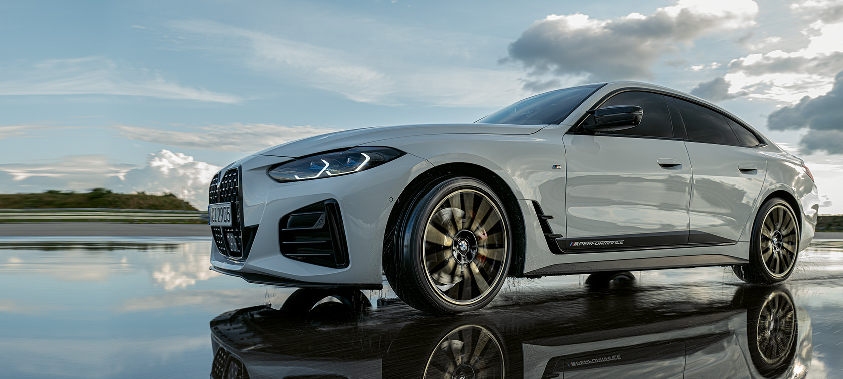 BMW 4 серії Gran Coupé (G26) з аксесуарами M Performance їде по мокрій вулиці BMW 4 серії Gran Coupé (G26) з аксесуарами M Performance їде по мокрій вулиці