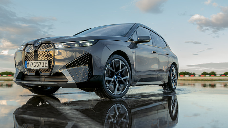 Колеса BMW, вид у три чверті спереду BMW iX (i20) на мокрій вулиці Колеса BMW, вид у три чверті спереду BMW iX (i20) на мокрій вулиці