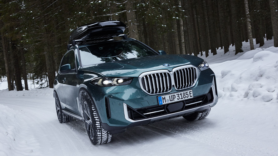 Зимові комплектні колеса BMW на BMW X5 (G05 LCI) на засніженій дорозі в лісі Зимові комплектні колеса BMW на BMW X5 (G05 LCI) на засніженій дорозі в лісі