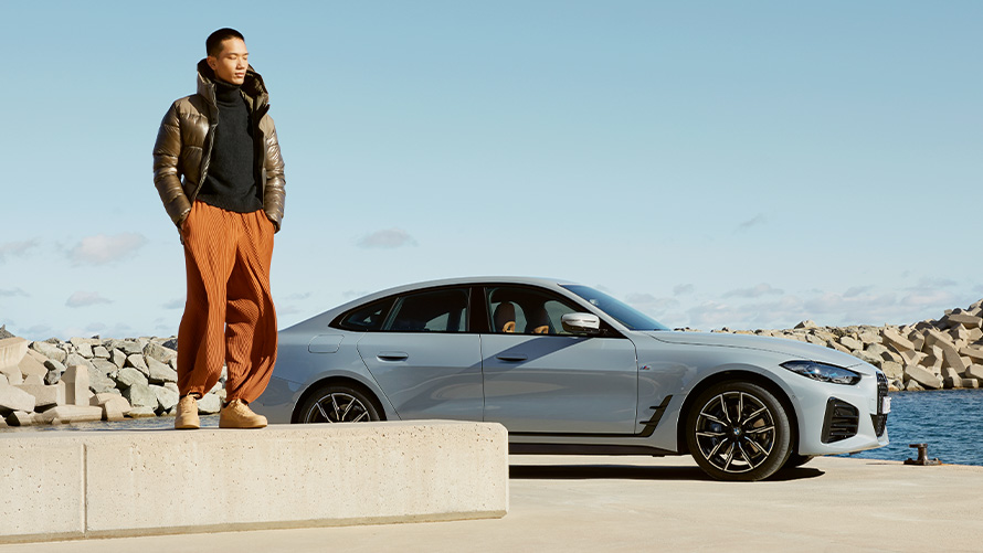 BMW Service Inclusive BMW Service Inclusive,  BMW G26, чоловік стоїть на краю каменя на тлі автомобіля BMW