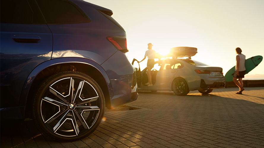 Обслуговування коліс і шин BMW Обслуговування коліс та шин BMW, BMW X1 U11 з двома людьми в автомобілі BMW на тлі сонця