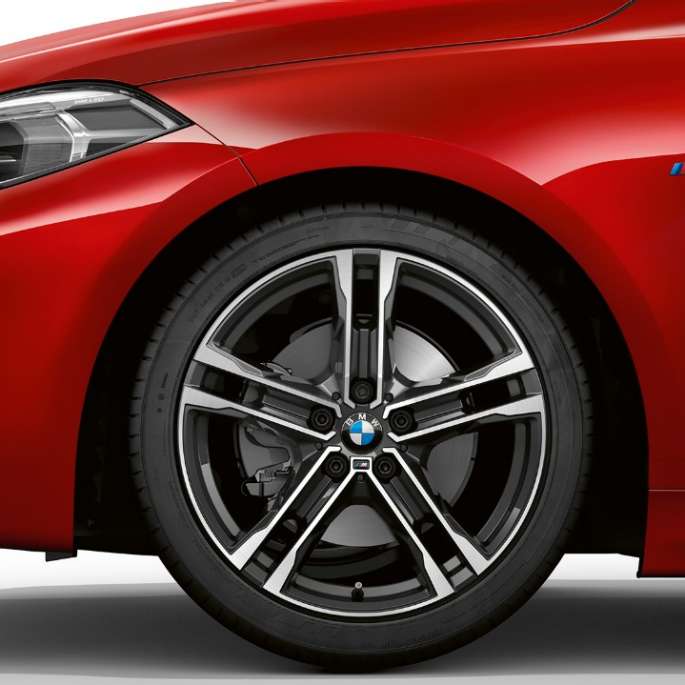 BMW 1 серії модель M Sport в Melbourne Red металік, спереду збоку з 17-дюймовими легкосплавними дисками M з подвійними спицями, стиль 550 M, двоколірні.