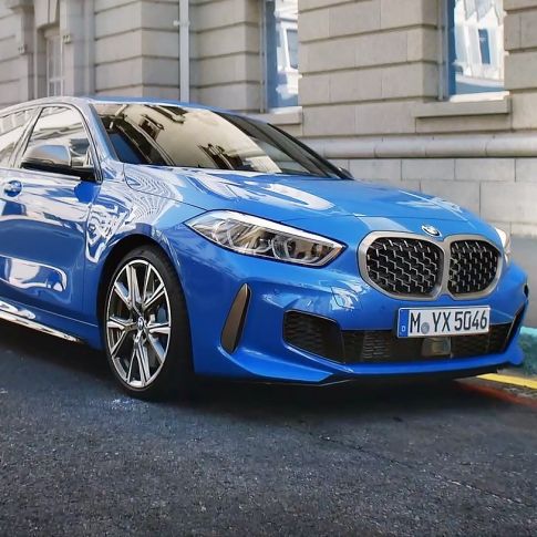 BMW 1 серії, вид спереду з поворотом в три чверті на узбіччі. BMW 1 серії в кольорі Misano Blue металік, вид спереду з поворотом в три чверті, парковка на узбіччі.
